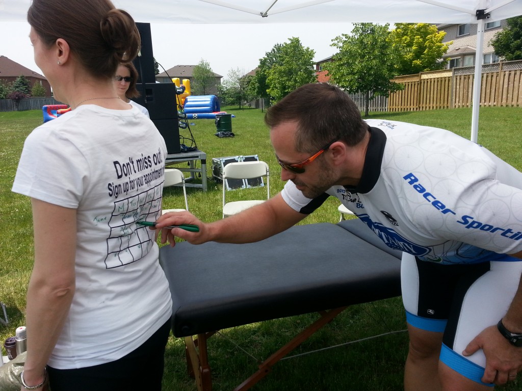 A cyclist signing up for their appointment on the back of physiotherapist, Jen Denys' shirt